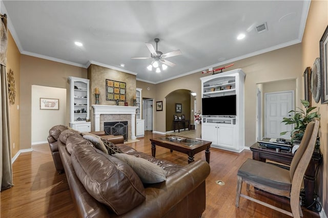 living room featuring crown molding, a fireplace, ceiling fan, and hardwood / wood-style flooring