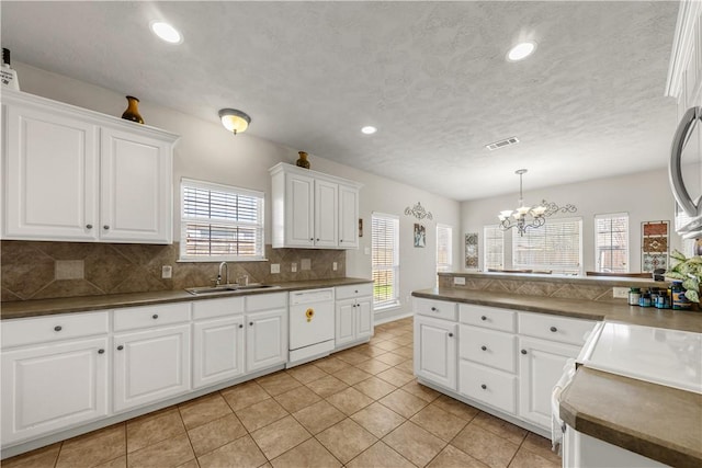 kitchen featuring white cabinetry, dishwasher, sink, a notable chandelier, and backsplash