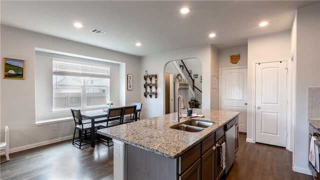 kitchen featuring visible vents, arched walkways, dark wood-style flooring, a sink, and dishwasher