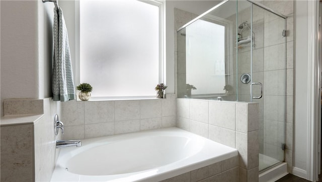 bathroom featuring a shower stall and a bath