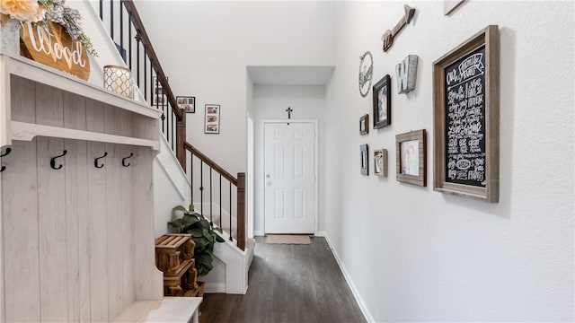 interior space with baseboards, a towering ceiling, and dark wood-style flooring