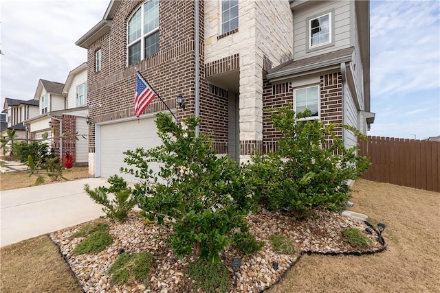 view of side of home featuring brick siding, driveway, and fence