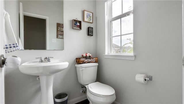 bathroom featuring toilet, baseboards, and a sink