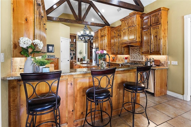 kitchen with light tile patterned floors, tasteful backsplash, stone countertops, lofted ceiling with beams, and a notable chandelier