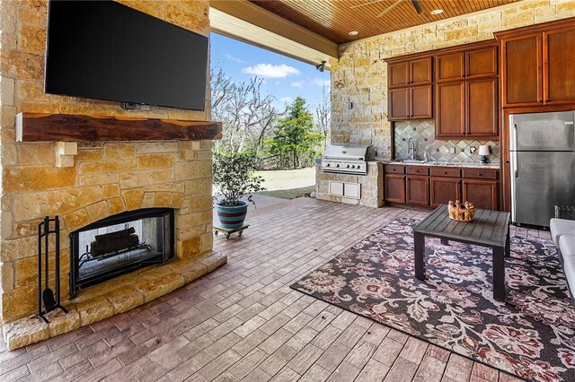 view of patio with exterior kitchen, an outdoor stone fireplace, a sink, and grilling area