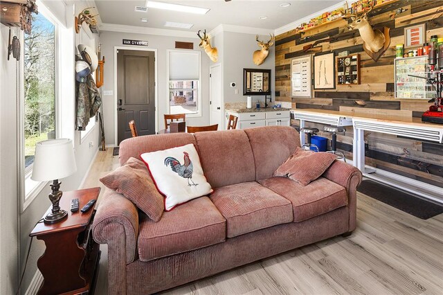 living room with visible vents, ornamental molding, and light wood-style flooring