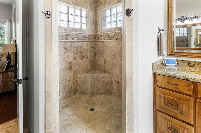 bathroom with a tile shower and vanity