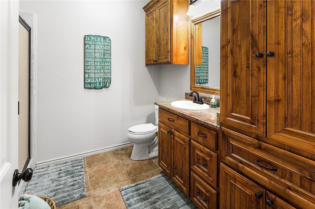 bathroom with vanity, toilet, and baseboards