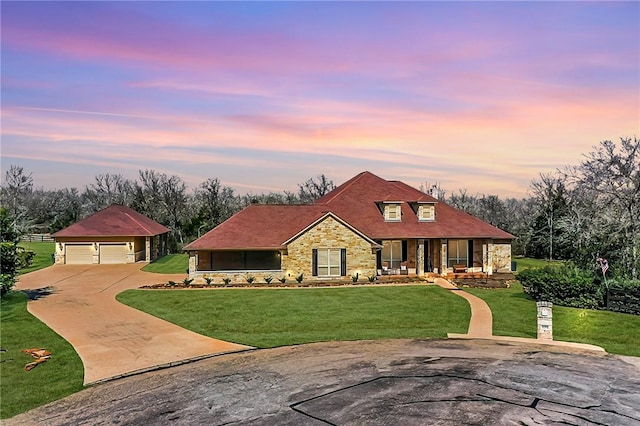 view of front of home with a garage, a lawn, stone siding, an outbuilding, and covered porch