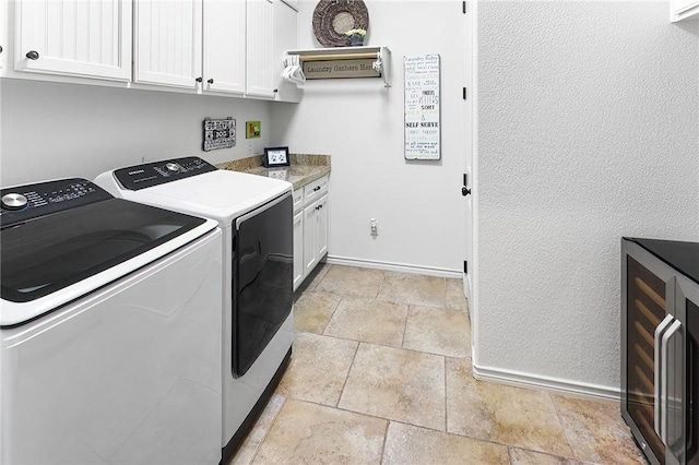 laundry room with stone tile flooring, cabinet space, baseboards, and separate washer and dryer