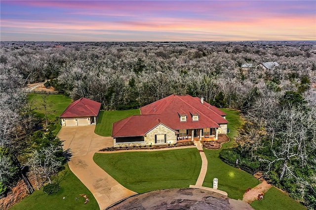 aerial view at dusk featuring a forest view