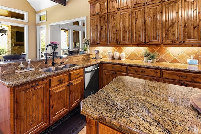 kitchen featuring stone counters, a peninsula, a sink, backsplash, and dishwasher