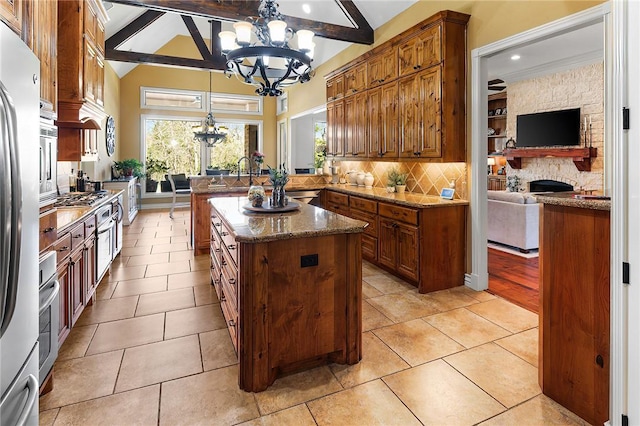 kitchen featuring lofted ceiling with beams, a peninsula, stainless steel appliances, tasteful backsplash, and brown cabinetry