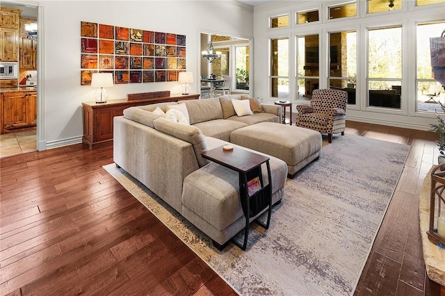 living area featuring crown molding, hardwood / wood-style floors, baseboards, and an inviting chandelier