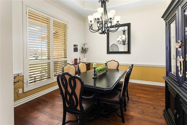 dining space featuring dark wood-style floors, a tray ceiling, crown molding, and an inviting chandelier