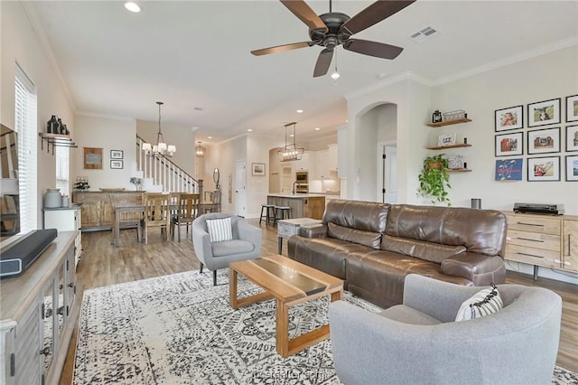 living room featuring ceiling fan with notable chandelier, light hardwood / wood-style flooring, and ornamental molding