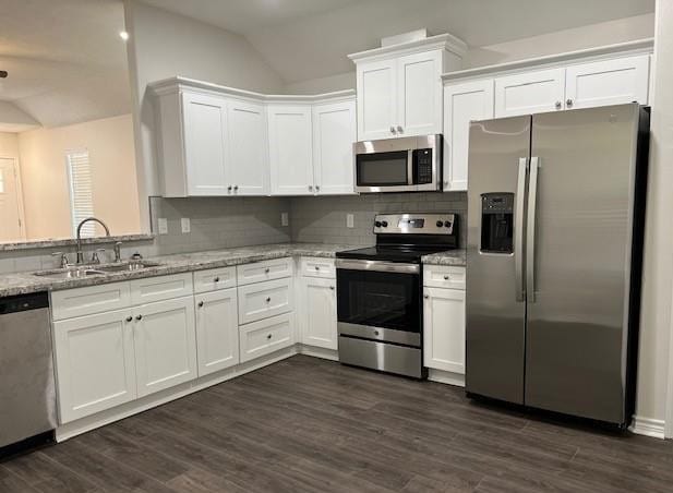1207 N Houston Ave, Bryan, TX 77803 - kitchen with stainless steel appliances, a sink, lofted ceiling, white cabinets, and light stone counters