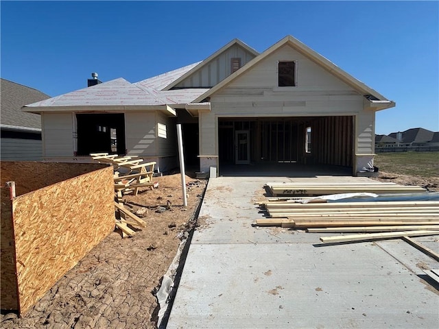 unfinished property featuring a garage, driveway, and board and batten siding