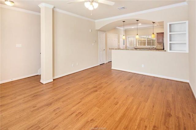 unfurnished living room featuring built in shelves, light hardwood / wood-style floors, ceiling fan, and crown molding