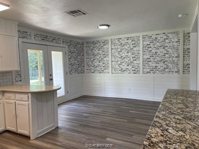 kitchen featuring kitchen peninsula, white cabinetry, dark wood-type flooring, and french doors