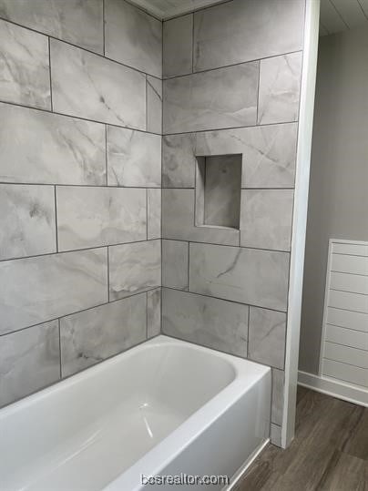 bathroom with hardwood / wood-style floors and tiled shower / bath combo