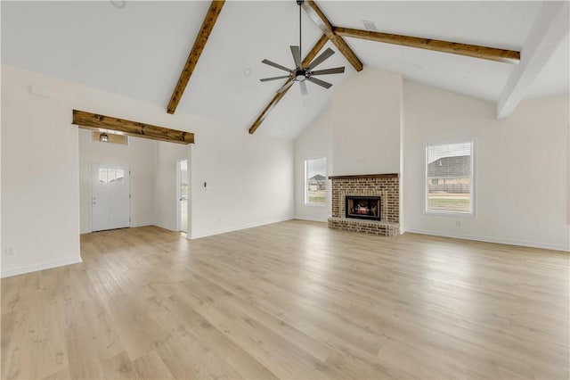 unfurnished living room with high vaulted ceiling, beamed ceiling, ceiling fan, a fireplace, and light hardwood / wood-style floors