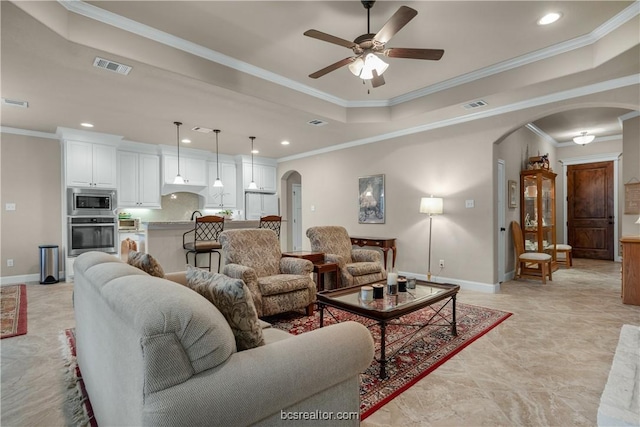 living room with a tray ceiling, ceiling fan, and ornamental molding