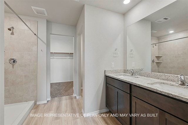103 Comal Dr, Huntsville, TX 77340 - bathroom with double vanity, a tile shower, a walk in closet, and wood finished floors