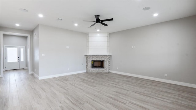 unfurnished living room featuring a brick fireplace, ceiling fan, and light hardwood / wood-style flooring