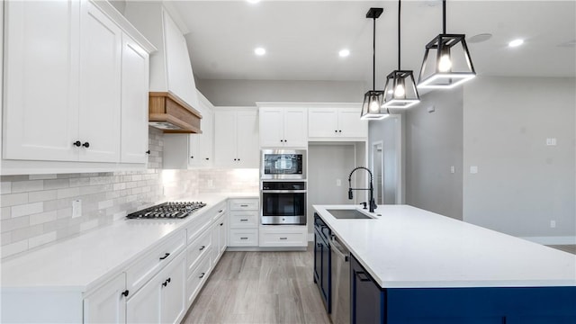 kitchen featuring stainless steel appliances, decorative light fixtures, sink, and white cabinets