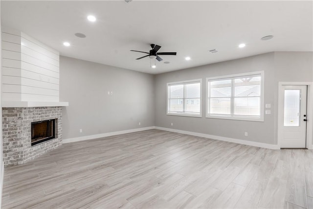 unfurnished living room with a brick fireplace, light hardwood / wood-style floors, and ceiling fan