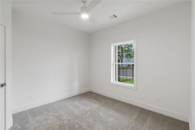 carpeted spare room with baseboards, a ceiling fan, and visible vents