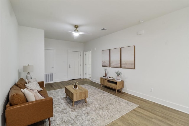 living room featuring visible vents, wood finished floors, baseboards, and ceiling fan