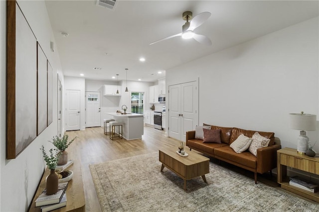 living area with a ceiling fan, light wood-type flooring, visible vents, and recessed lighting
