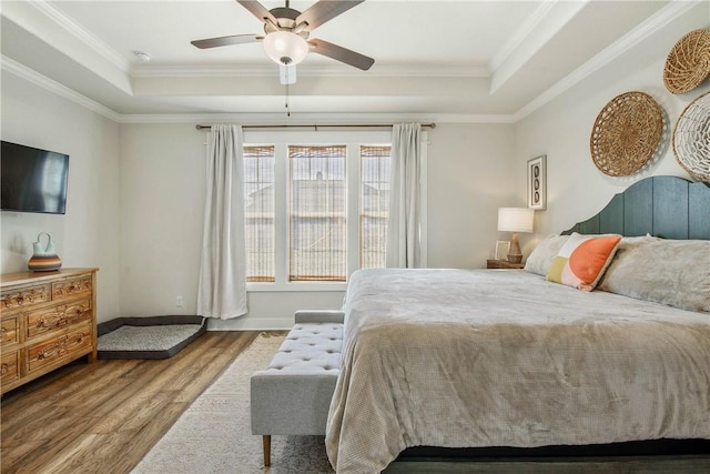 bedroom featuring a tray ceiling, ceiling fan, wood-type flooring, and ornamental molding