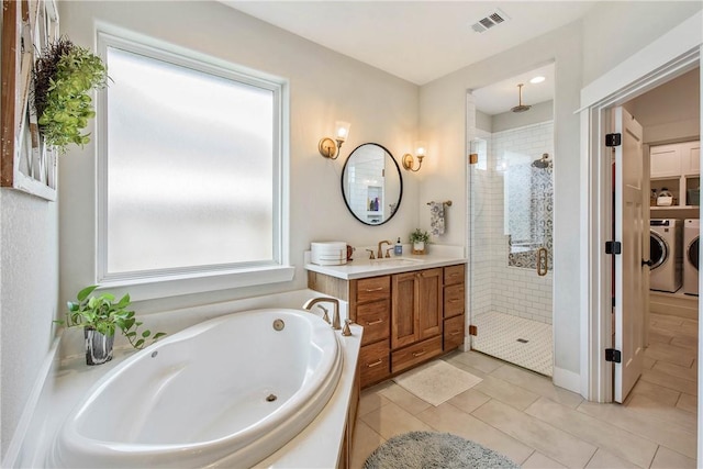 bathroom with tile patterned flooring, vanity, independent shower and bath, and washing machine and clothes dryer