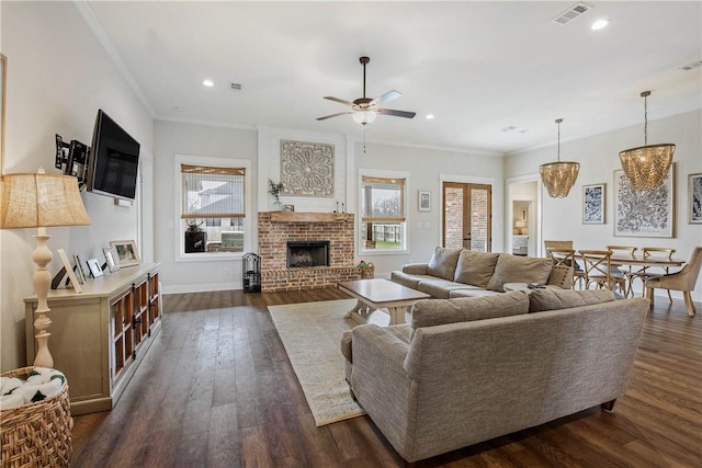 living room with french doors, ceiling fan with notable chandelier, ornamental molding, a fireplace, and dark hardwood / wood-style flooring