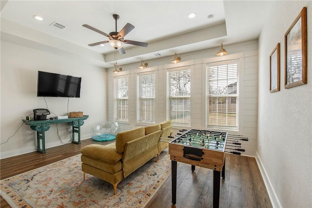 playroom with a raised ceiling, ceiling fan, and dark hardwood / wood-style flooring