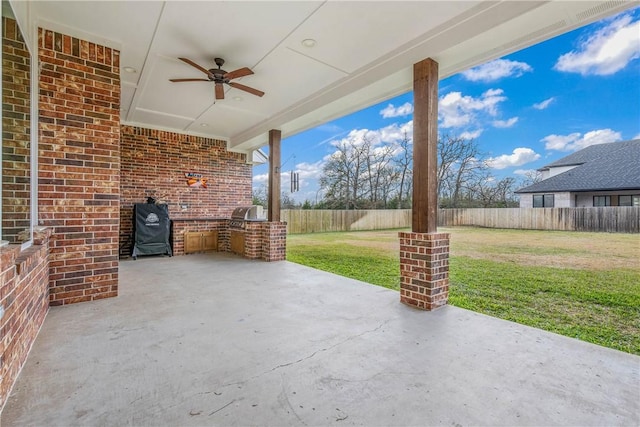 view of patio with ceiling fan, area for grilling, and exterior kitchen