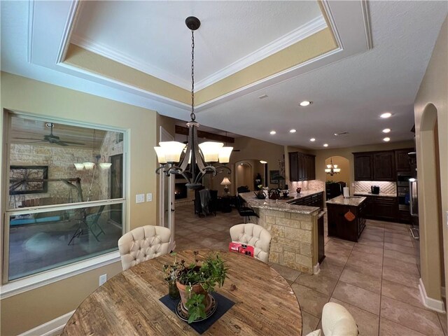 1142 Fletcher, Anderson, TX 77830 - dining space featuring arched walkways, a chandelier, light tile patterned floors, a ceiling fan, and crown molding