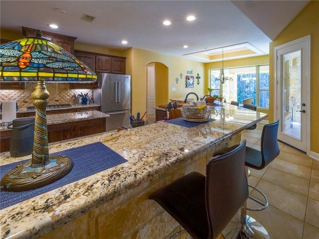 1142 Fletcher, Anderson, TX 77830 - kitchen featuring stainless steel appliances, arched walkways, light tile patterned floors, light stone countertops, and a chandelier