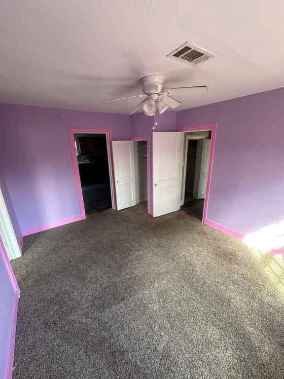 unfurnished bedroom with a closet, dark carpet, and ceiling fan