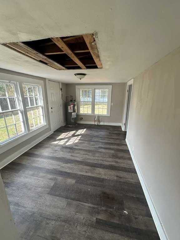 unfurnished room with dark hardwood / wood-style flooring, electric water heater, and a healthy amount of sunlight