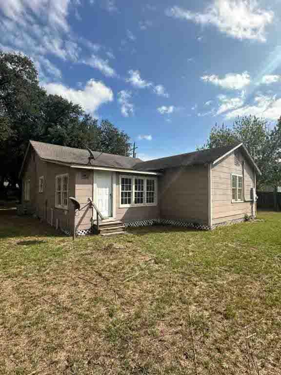 rear view of property featuring a lawn