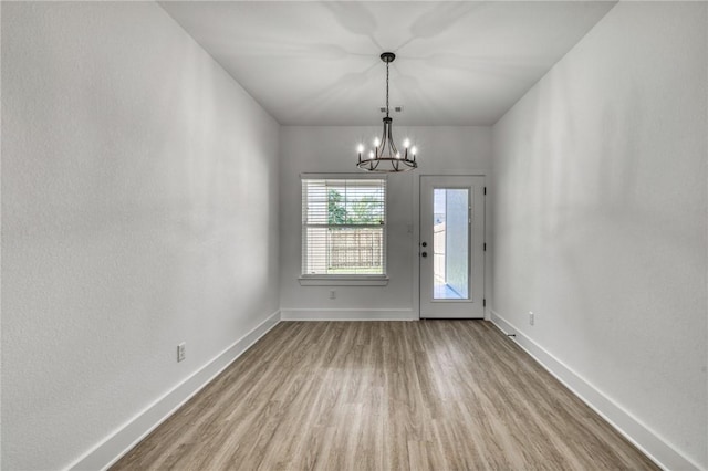 spare room with light hardwood / wood-style flooring and a chandelier