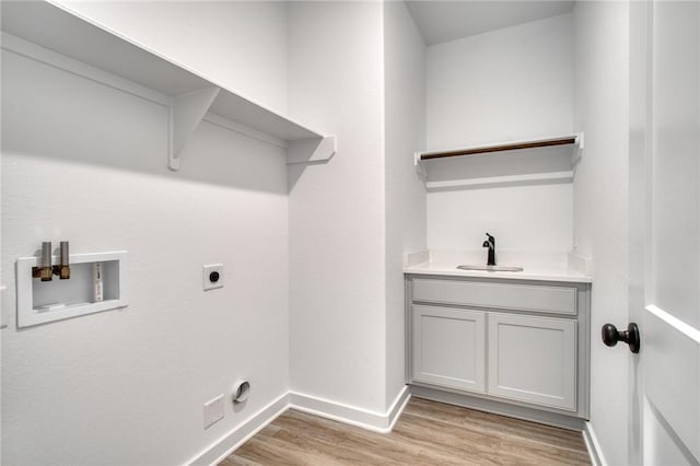 laundry area with hookup for an electric dryer, hookup for a washing machine, light wood-type flooring, and sink