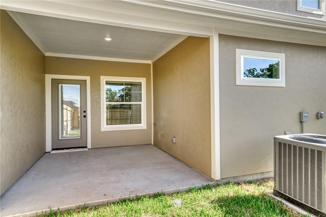 view of exterior entry featuring central AC and a patio area