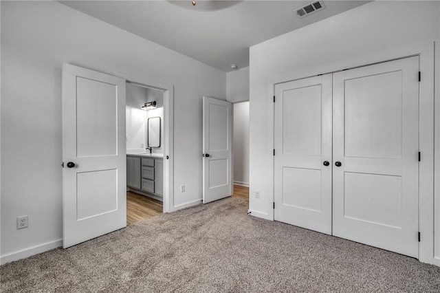 unfurnished bedroom featuring light colored carpet, sink, connected bathroom, and a closet