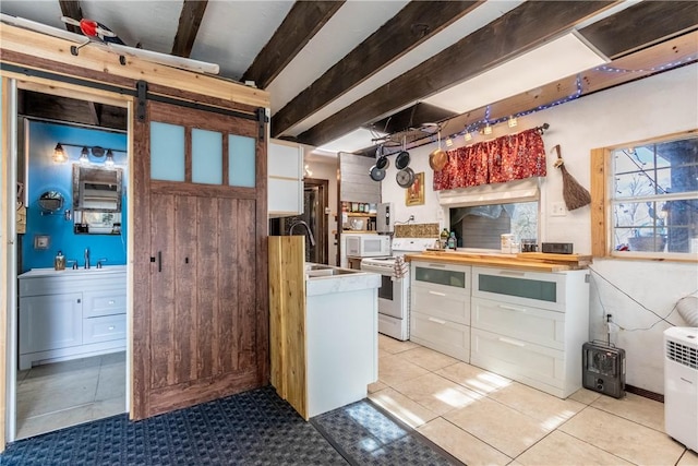 kitchen with a barn door, white appliances, a sink, white cabinetry, and beamed ceiling