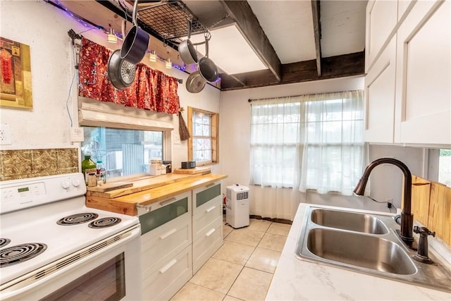 kitchen featuring white electric range, light tile patterned flooring, a sink, and white cabinetry